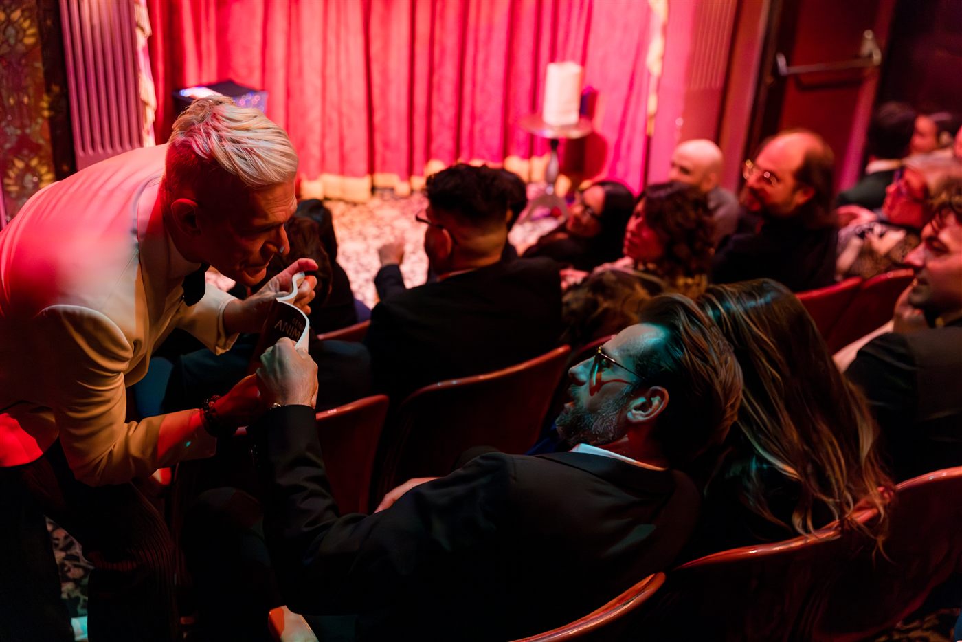 Felix Jones leaning into the audience to perform close-up magic in an intimate theater